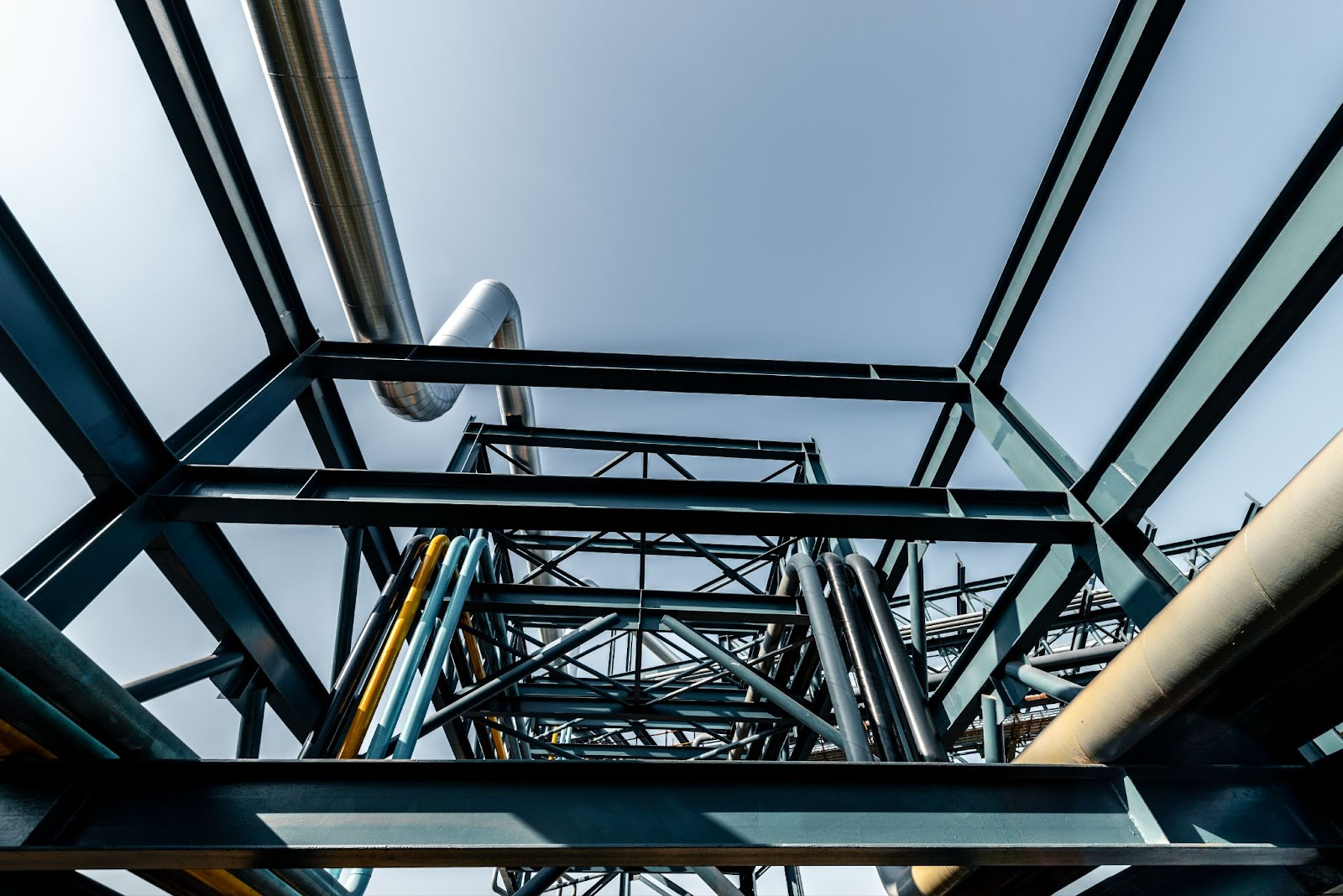 Complex industrial piping and structural steelwork of a heat exchanger from below, highlighting its intricate design.